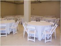 Round Table Setup with White Linens and White Resin Chairs